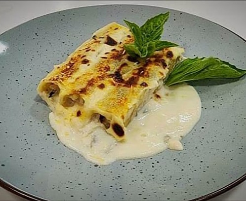 Canelones caseros gratinados con salsa bechamel y hojas de albahaca.