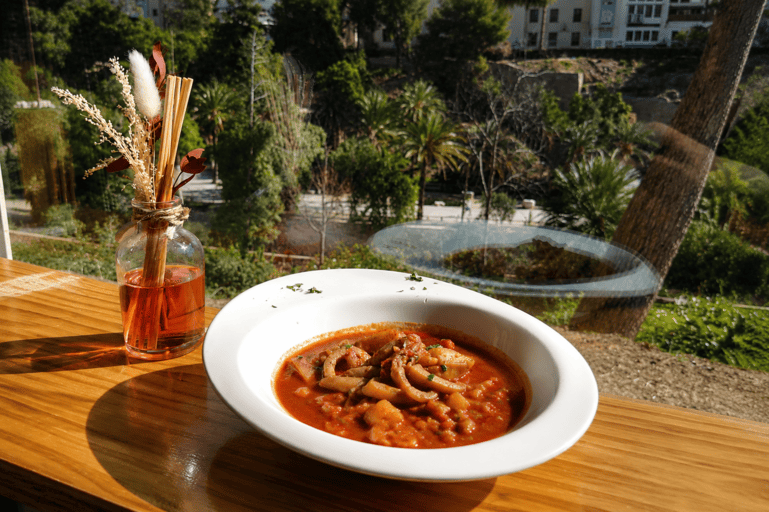 Plato de guiso tradicional servido en una mesa de terraza al aire libre.