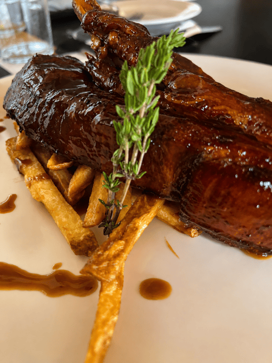 Costilla de carne glaseada en salsa barbacoa sobre cama de patatas fritas caseras.